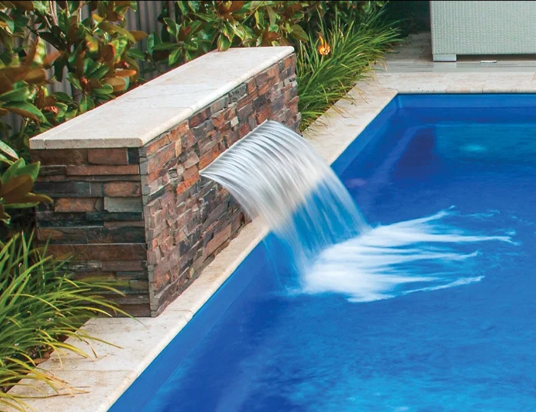 Stone water feature spilling into a pool